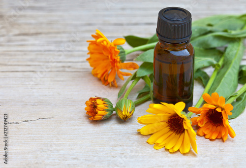 Healing bright calendula flowers and a vial with a medicinal tincture based on a marigold plant. Place for text. Close-up view