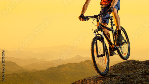 Cyclist Riding the Bike Down the Rock at Sunset. Extreme Sport and Enduro Biking Concept.
