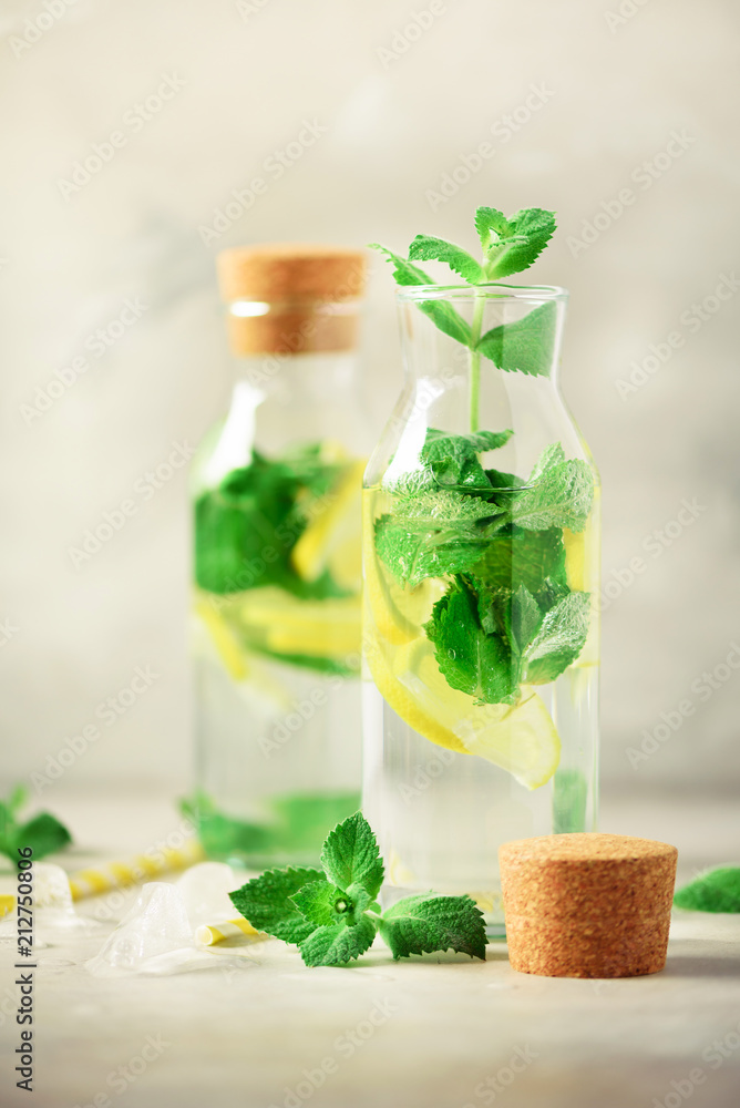 Citrus lemonade - mint, lemon and tropical monstera leaves on grey background. Detox drink. Summer fruit infused water. Copy space. Citrus lemonade - mint, lemon and tropical monstera leaves on grey background. Detox drink. Summer fruit infused water. Copy space.