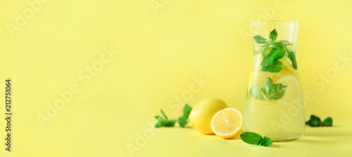 Detox water with mint, lemon on yellow background. Banner with copy space. Citrus lemonade. Summer fruit infused water.