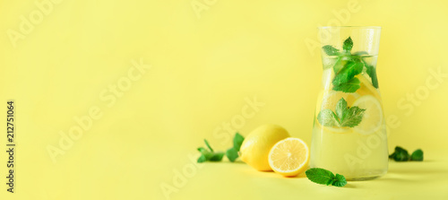 Detox water with mint, lemon on yellow background. Banner with copy space. Citrus lemonade. Summer fruit infused water. photo