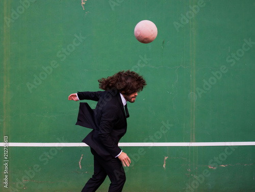 man with long hair wearing a suit playing with a ball © marc