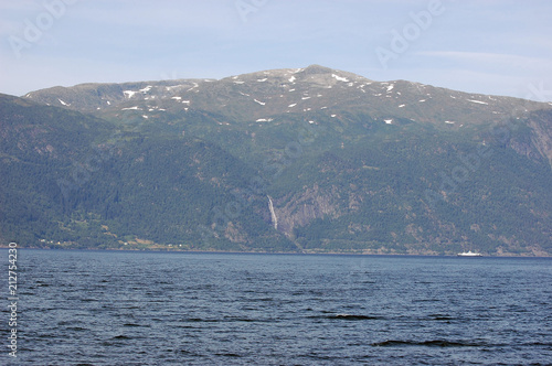 Mountains and fjord in Norway. Clouds and blue sky. Beautiful stunning views of mountains, water, sky, clouds and sun. Norwegian nature. Sognefjord 