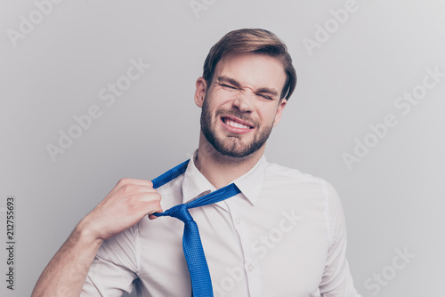 Close up portrait of exhausted frustrated stressed handsome sad unhappy upset entrepreneur trying to take off uncomfortable blue tie formal wear isolated on gray background copy-space photo