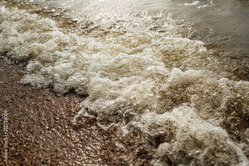 Soft wave of the blue sea on a sandy beach.