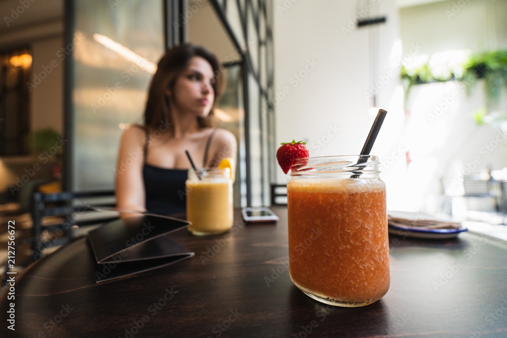 Smoothie standing on table near woman Smoothie standing on table near woman
