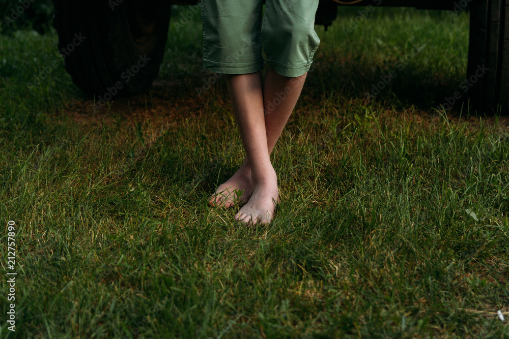 Foot over green grass. bare feet to stand on the green grass. in green shorts near the car