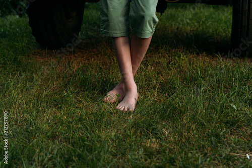 Foot over green grass. bare feet to stand on the green grass. in green shorts near the car