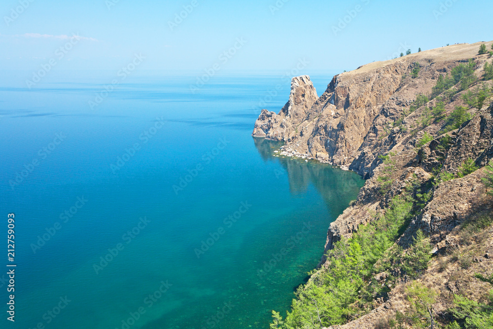 Lake Baikal in the summer. The northern extremity of Olkhon Island is Cape Khoboy. Small figures of tourists visiting the cliff - a natural landmark island