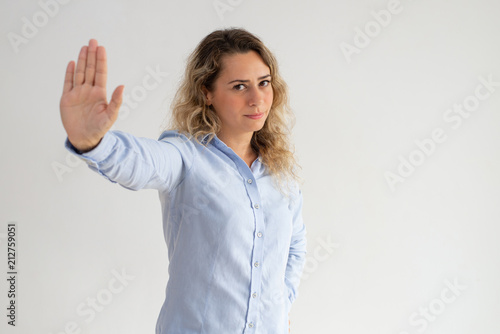 Serious displeased woman making stop gesture. Disappointed lady rejecting and gesturing while looking at camera. Cancelation concept 