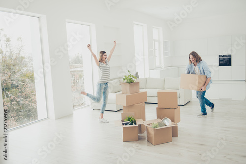 Dreams come true! Long-awaited moment! Order furniture day property rejoice delight concept. Inspired beautiful lady raising hands up singing dancing in brand new white spacious living room