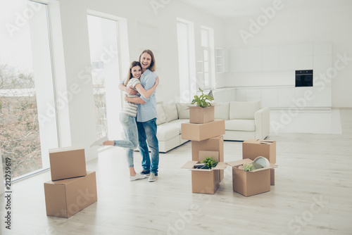 We did it! Rent property happiness furniture concept. Joyful lovely rejoicing beautiful handsome cheerful people in casual denim clothes standing in white spacious room around open boxes with things