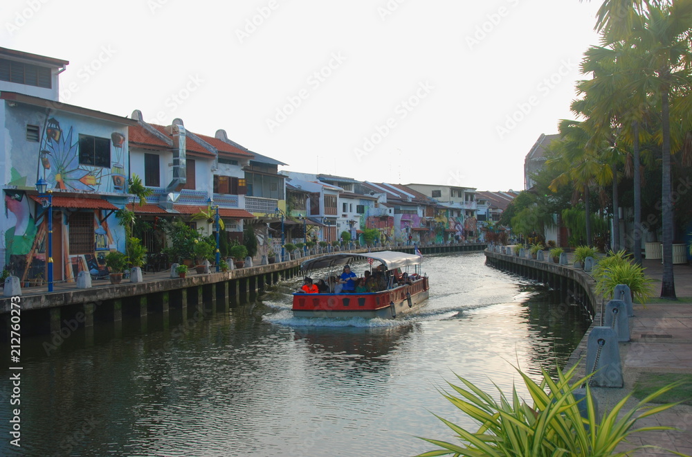 Obraz premium A boat going on canal through city centre of Melaka around colorful houses