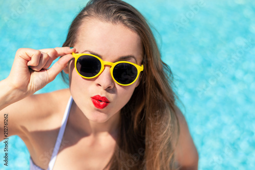 Summertime in pool. Young woman with yellow sunglasses in pool.