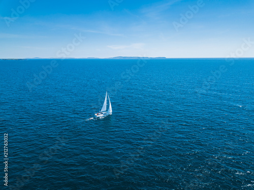 Aerial drone bird's eye view of sail boat cruising in the Aegean deep blue sea