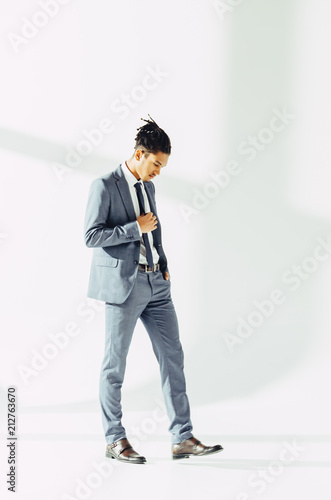 Professional african american businessman in thinking posture over grey background.
