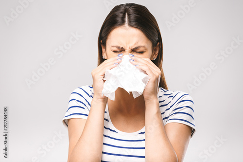 People, healthcare, rhinitis, cold and allergy concept - unhappy woman with paper napkin blowing nose