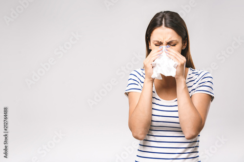 People, healthcare, rhinitis, cold and allergy concept - unhappy woman with paper napkin blowing nose photo