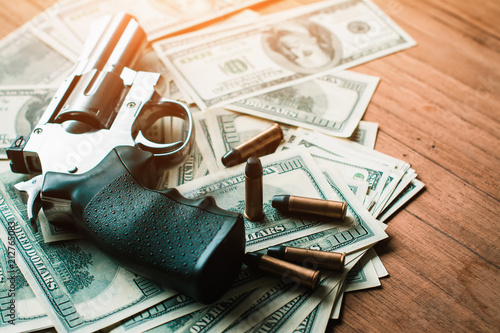 Corruption concept, with guns and dollar bills placed on wooden boards.