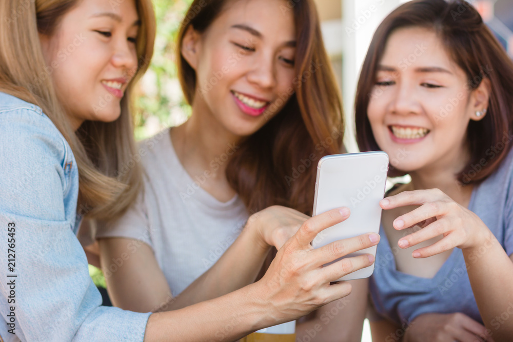 Cheerful asian young women sitting in cafe drinking coffee with friends and talking together. Attractive asian woman enjoying coffee while using smartphone for talking, reading and texting. Cheerful asian young women sitting in cafe drinking coffee with friends and talking together. Attractive asian woman enjoying coffee while using smartphone for talking, reading and texting.