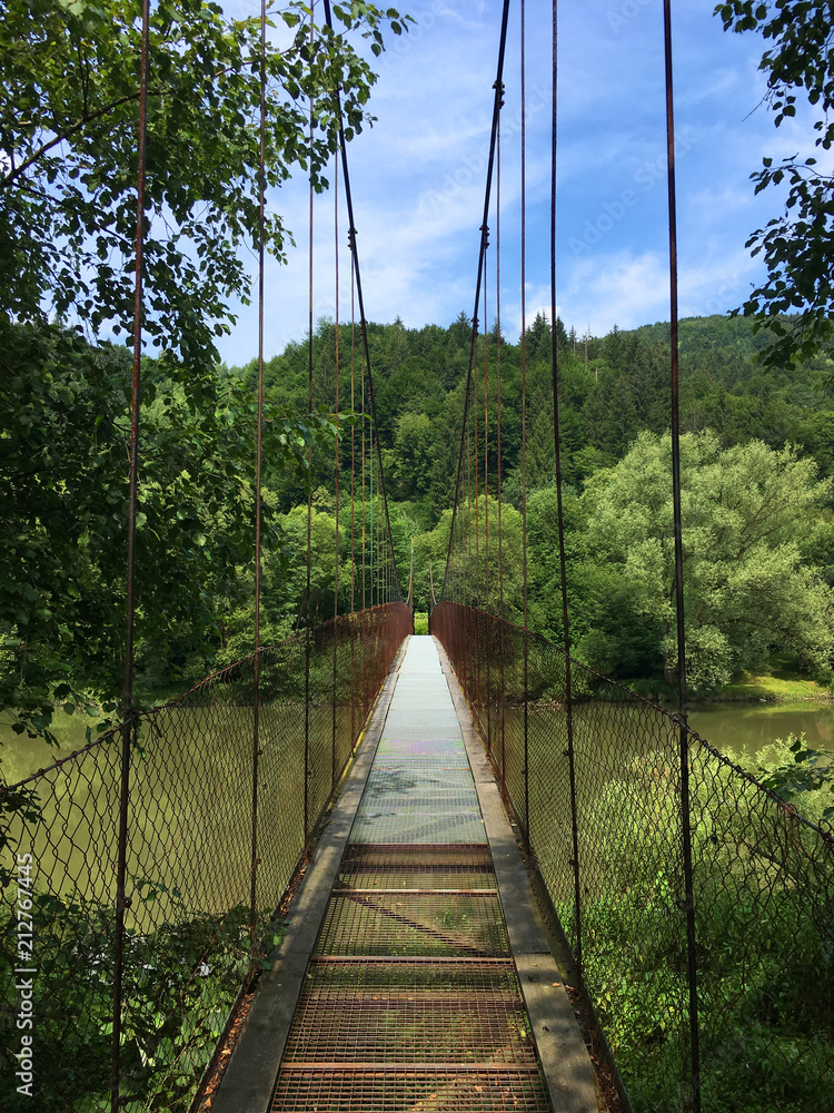 Obraz premium suspended bridge for pedestrians, symmetrical view, Orava river, Slovakia