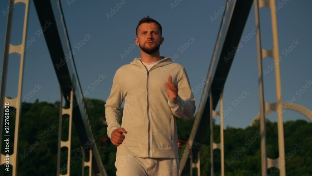 Healthy young man jogging in the city on a sunny morning. Morning runner looks relaxed and focused. Healthy young man jogging in the city on a sunny morning. Morning runner looks relaxed and focused.