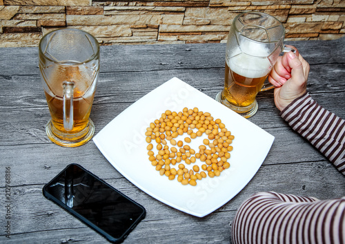 A woman sitting in a bar and holding a glass of light beer.