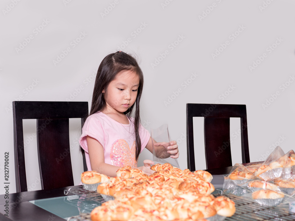 Adorable kid girl separate packing baked pork sausage with mayonnaise bread, domestic kitchen, Child helping his parents Adorable kid girl separate packing baked pork sausage with mayonnaise bread, domestic kitchen, Child helping his parents