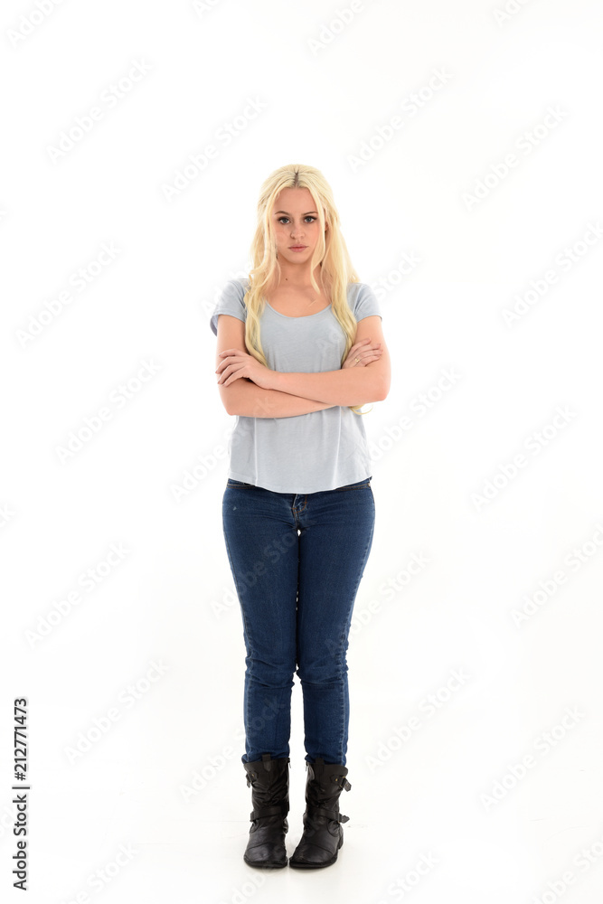 full length portrait of blonde girl wearing blue shirt and jeans, standing pose isolated on white studio background.