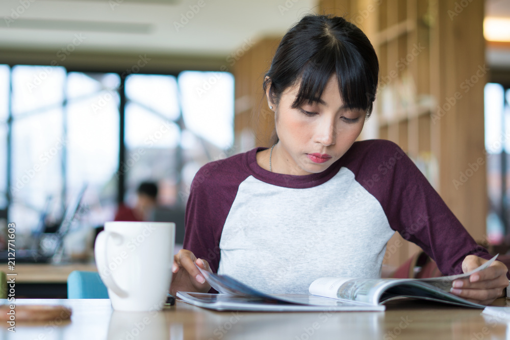 Charming girl sitting by wooden table and reading book Charming girl sitting by wooden table and reading book