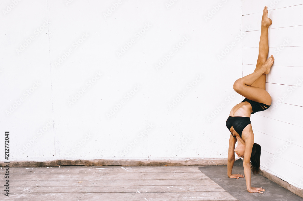Attractive brunette woman doing yoga exercises in sexual bikini on a white background Attractive brunette woman doing yoga exercises in sexual bikini on a white background