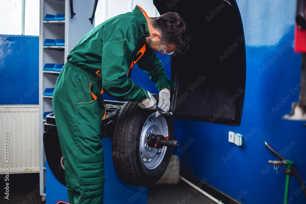 Mechanic removes car tire and balancing wheels Mechanic removes car tire and balancing wheels