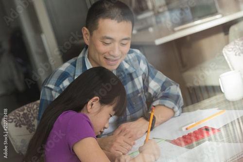 Father assisting her daughter in doing homework photo