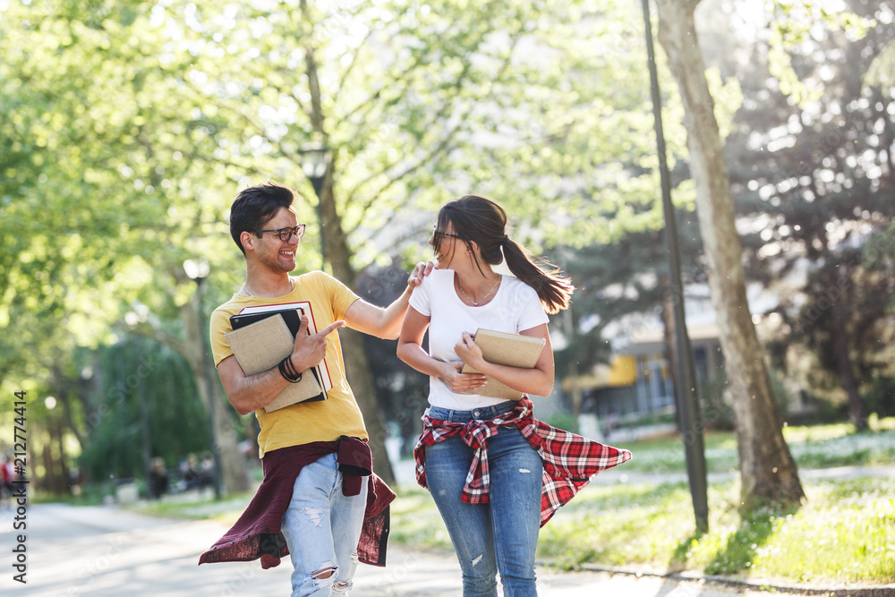 Young student couple going to college class.They walks trough university campus and laughing. Young student couple going to college class.They walks trough university campus and laughing.