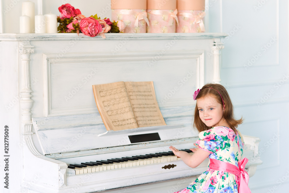 little girl in white dress playing the piano. Music and art concept. School of Music little girl in white dress playing the piano. Music and art concept. School of Music