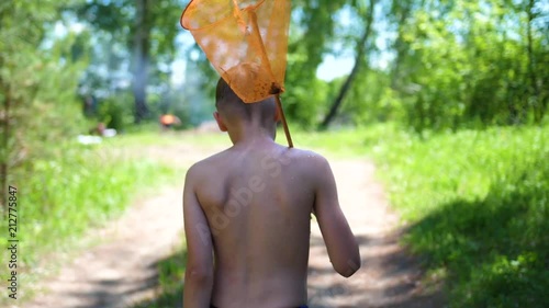 The guy after fishing is on a forest road. In the hands of holds net. Hot summer day. Summer vacation in the village. photo