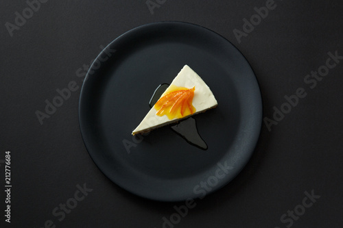 Dessert of cheesecake with jam on a black plate isolated on a black background