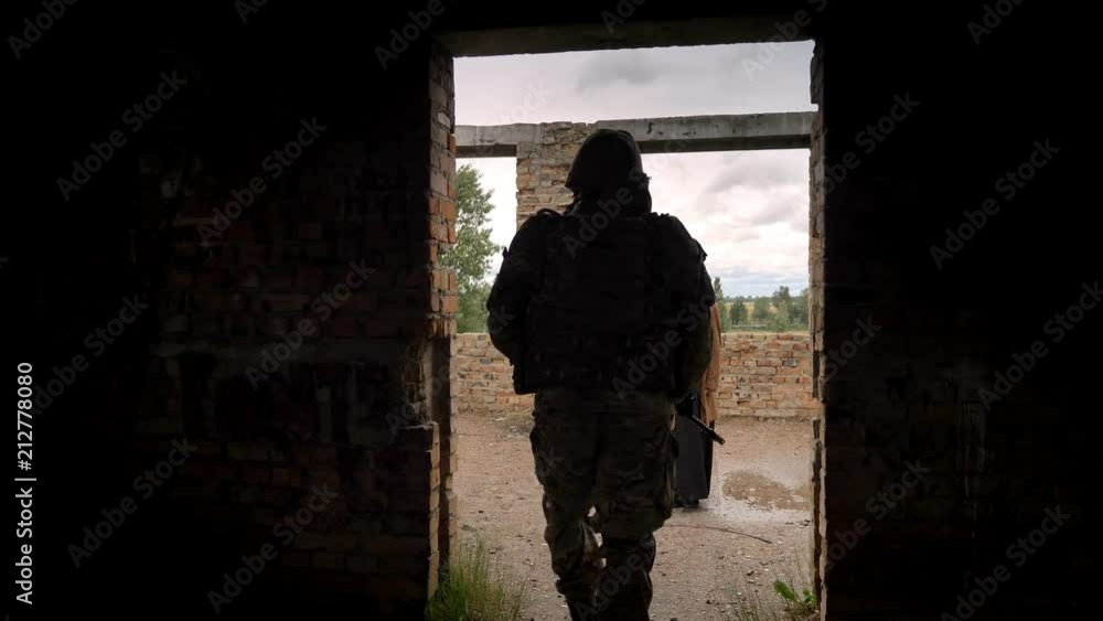 Soldier with weapon passing by young woman in ruined building Soldier with weapon passing by young woman in ruined building