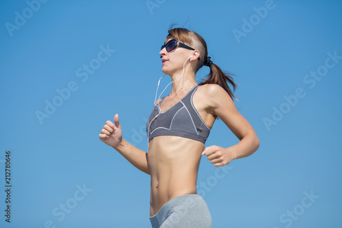 Sportswoman jogging on background of clear sky