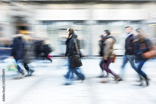 Large group of people walking in front of shop window, blue toned image