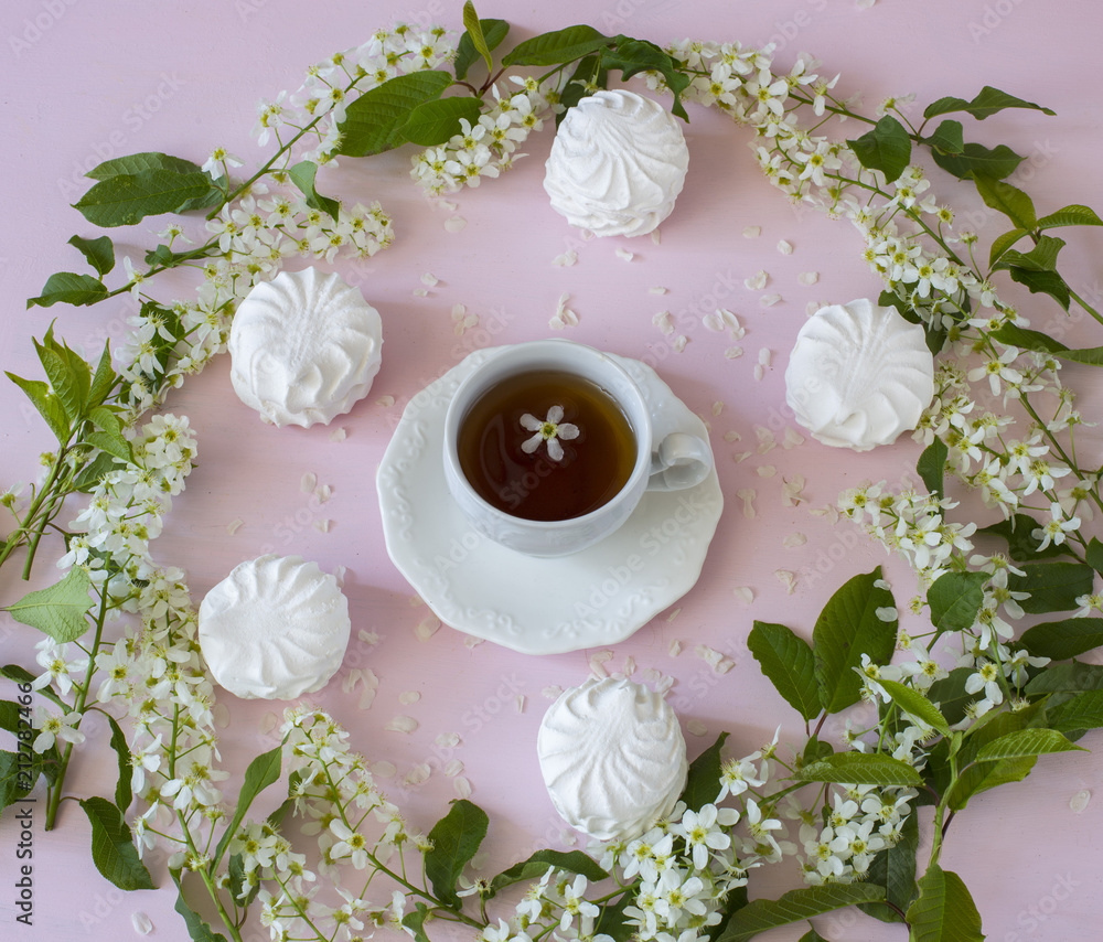 a circle of bird cherry, marshmallow and a cup of tea on a pink background a circle of bird cherry, marshmallow and a cup of tea on a pink background