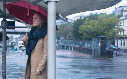 Woman holding umbrella while standing at bus stop photo