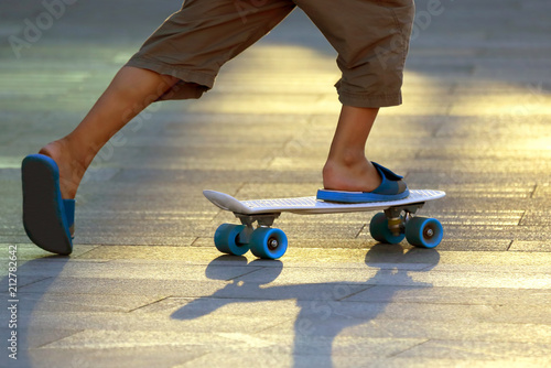 the legs of a teenager rolling on a skateboard.