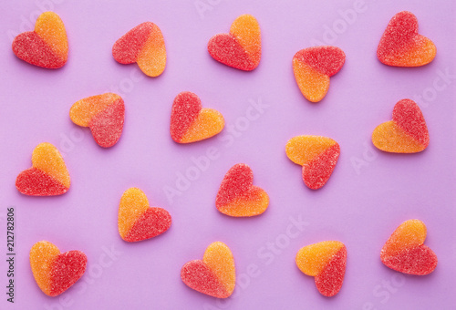 Heart shaped candy pattern on a purple background. Jelly candies viewed from above. Top view. Repetition concept