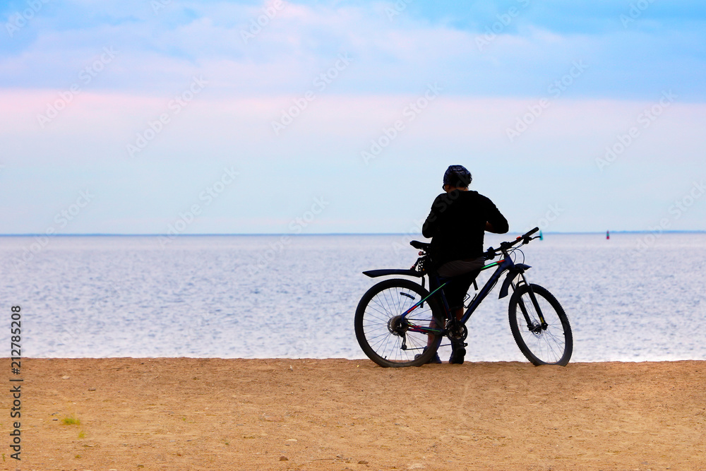 Fototapeta premium the bicyclist on the shore sea looks into the distance