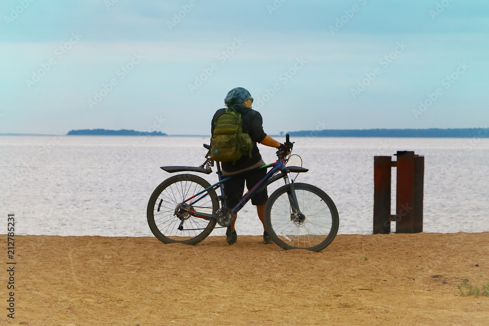 Fototapeta premium the bicyclist on the shore sea looks into the distance