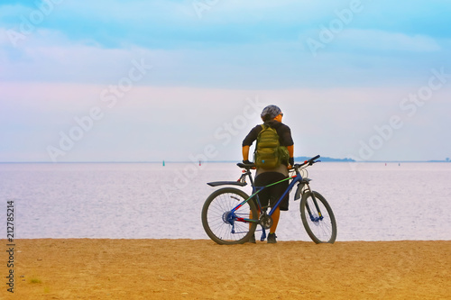 the bicyclist on the shore sea looks into the distance