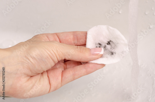 Wadded disc in hand wash off make-up washbasin bathroom