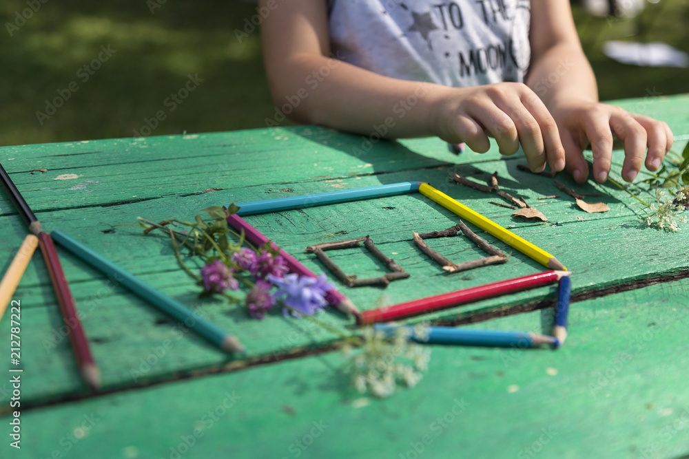 Obraz premium the child draw picture with colorful pens and flowers on the wooden green table in the nursery or school for activity concept. creative ideas for child development.