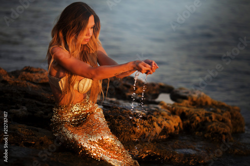 Beautiful mermaid sitting on a rock